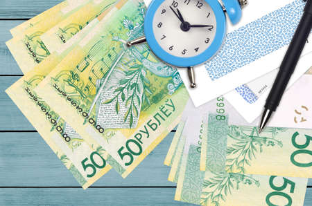 50 Belorussian rubles bills and alarm clock with pen and envelopes. Tax season concept, payment...
