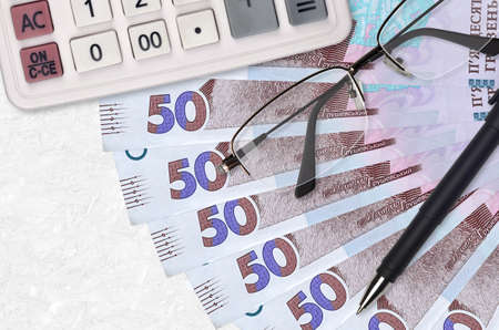 50 Ukrainian hryvnias bills fan and calculator with glasses and pen. Business loan or tax payment...