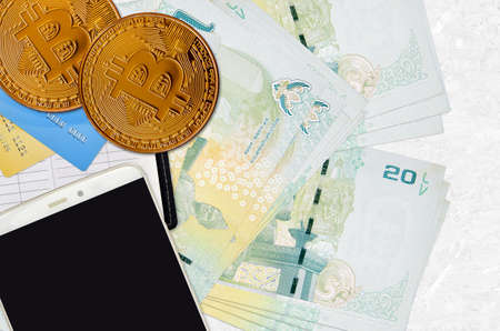 20 Thai Baht bills and golden bitcoins with smartphone and credit cards. Cryptocurrency investment...