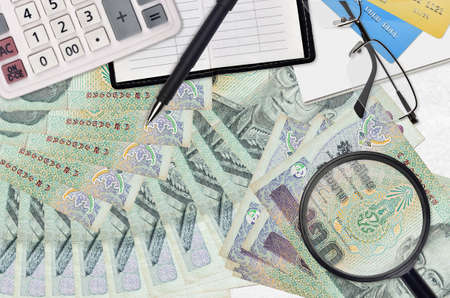20 Thai Baht bills and calculator with glasses and pen. Tax payment season concept or investment solutions. Searching a job with high salary earningsの写真素材