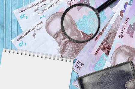 50 Ukrainian hryvnias bills and magnifying glass with black purse and notepad. Concept of...