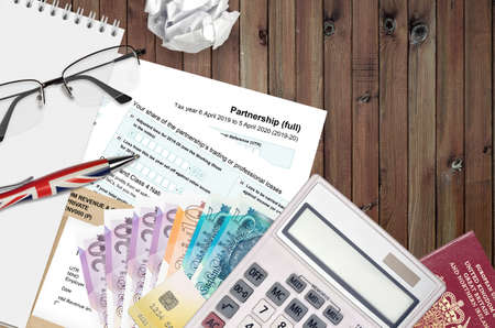 English Tax form sa104 Partnership from HM revenue and customs lies on table with office items. HMRC...
