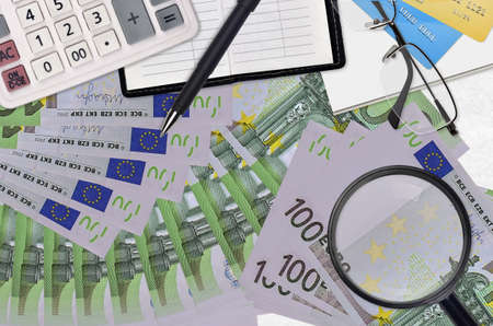 100 Euro bills and calculator with glasses and pen. Tax payment season concept or investment solutions. Searching a job with high salary earningsの写真素材