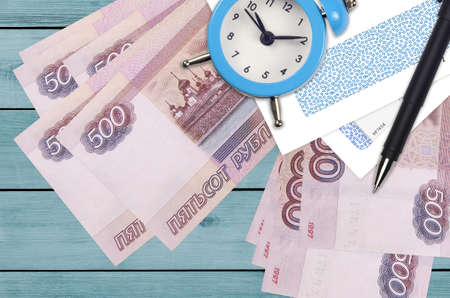 500 russian rubles bills and alarm clock with pen and envelopes. Tax season concept, payment deadline for credit or loan. Financial operations using postal service. Quick money transferの写真素材