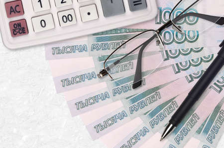 1000 russian rubles bills fan and calculator with glasses and pen. Business loan or tax payment...