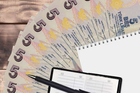 5 Turkish lira bills fan and notepad with contact book and black pen. Concept of financial planning...