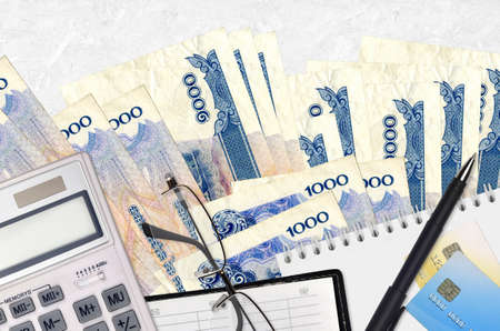 1000 Cambodian riels bills and calculator with glasses and pen. Tax payment season concept or...