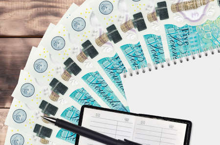 5 British pounds bills fan and notepad with contact book and black pen. Concept of financial...