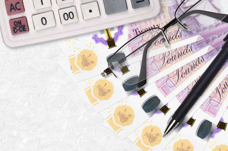 20 British pounds bills fan and calculator with glasses and pen. Business loan or tax payment season...