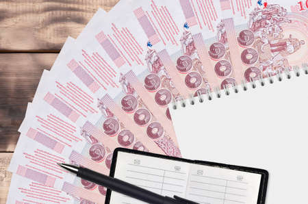 100 Thai Baht bills fan and notepad with contact book and black pen. Concept of financial planning...