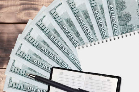 100 US dollars bills fan and notepad with contact book and black pen. Concept of financial planning...