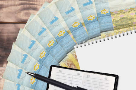 1 Ukrainian hryvnia bills fan and notepad with contact book and black pen. Concept of financial...