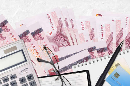 100 Thai Baht bills and calculator with glasses and pen. Tax payment season concept or investment solutions. Financial planning or accountant paperworkの写真素材