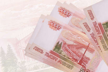 5000 russian rubles bills lies in stack on background of big semi-transparent banknote. Abstract...