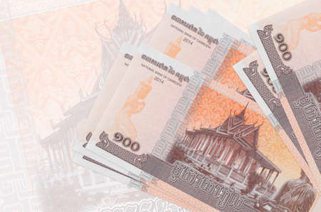 100 Cambodian riels bills lies in stack on background of big semi-transparent banknote. Abstract...