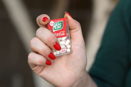KHARKOV, UKRAINE - OCTOBER 16 2020: Young girl holds Tic-tac hard mints pack with coca-cola taste. Tic Tac is a brand of small hard mints, produced by Ferreroのeditorial素材