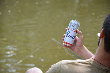 KHARKOV, UKRAINE - AUGUST 22 2020: Man holds Budweiser Lager Alcohol Beer during fishing. Budweiser is Brand from Anheuser-Busch Inbev most popular in Americaのeditorial素材