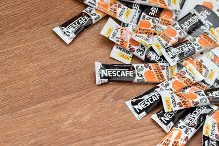KHARKOV, UKRAINE - MARCH 21, 2020: Many Nescafe caramel cream coffee sticks on wooden background. Nescafe is a brand of coffee made by Nestle, swiss multinational conglomerate corporationのeditorial素材