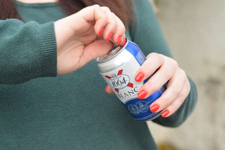 KHARKOV, UKRAINE - OCTOBER 16, 2020: Young girl holds 1664 Kronenbourg Blanc beer can outdoors. 1664...
