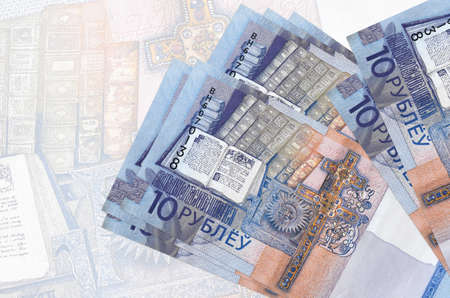 10 Belorussian rubles bills lies in stack on background of big semi-transparent banknote. Abstract...