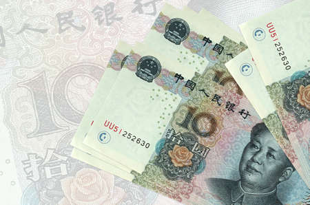 10 Chinese yuan bills lies in stack on background of big semi-transparent banknote. Abstract...