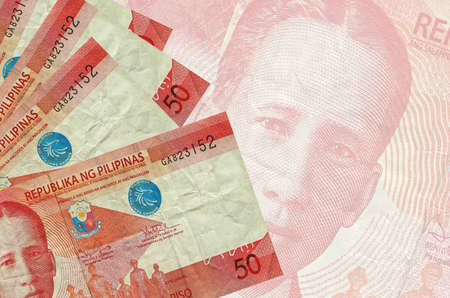 50 Philippine piso bills lies in stack on background of big semi-transparent banknote. Abstract...