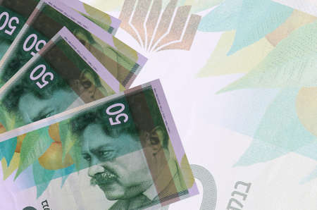 50 Israeli new shekels bills lies in stack on background of big semi-transparent banknote. Abstract...