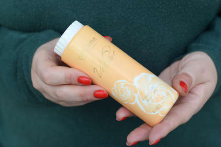 KHARKOV, UKRAINE - OCTOBER 16 2020: Young girl holds Oriflame Volare fragranced body talc. Oriflame Holding AG is a multi-level marketing cosmetics company founded in Sweden in 1967のeditorial素材