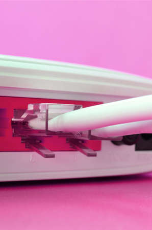 The Internet cable plugs are connected to the Internet router, which lies on a bright pink...