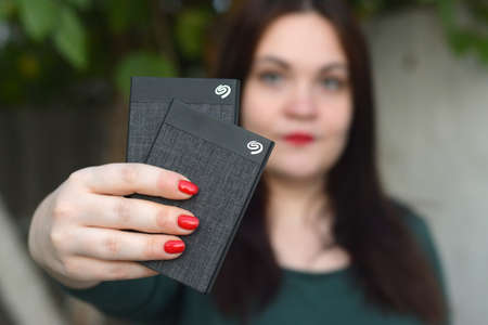 KHARKOV, UKRAINE - OCTOBER 16 2020: Young girl holds Seagate 1tb portable USB hard drive. Seagate Technology PLC is American data storage company was incorporated in 1978のeditorial素材