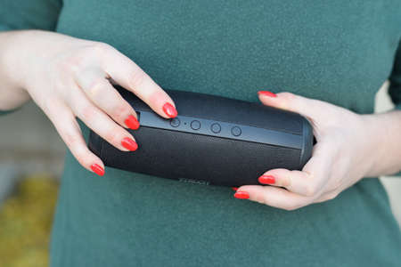 KHARKOV, UKRAINE - OCTOBER 16 2020: Young girl holds Nomi black portable USB speaker by Nomi...