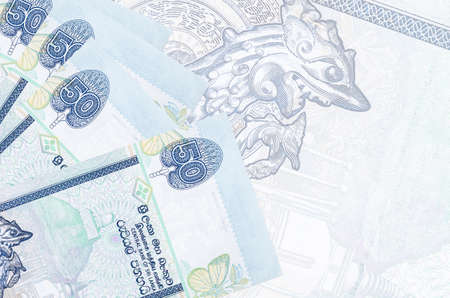 50 Sri Lankan rupees bills lies in stack on background of big semi-transparent banknote. Abstract...