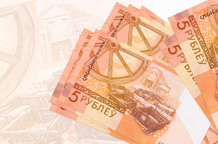 5 Belorussian rubles bills lies in stack on background of big semi-transparent banknote. Abstract...