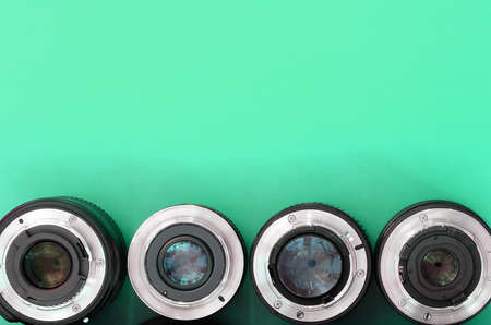 Several photographic lenses lie on a bright turquoise background. Space for textの写真素材