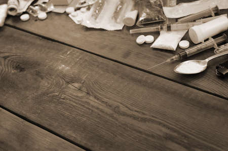 A lot of narcotic substances and devices for the preparation of drugs lie on an old wooden table....