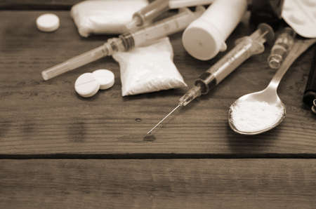 A lot of narcotic substances and devices for the preparation of drugs lie on an old wooden table....