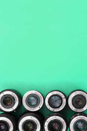 Several photographic lenses lie on a bright turquoise background. Space for textの写真素材