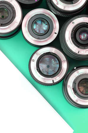 Several photographic lenses and white notebook lie on a bright turquoise background. Space for textの写真素材