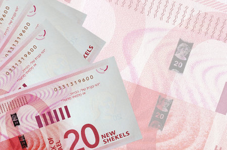 20 Israeli new shekels bills lies in stack on background of big semi-transparent banknote. Abstract business background with copy spaceの写真素材