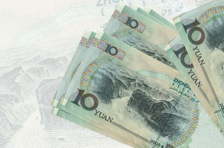 10 Chinese yuan bills lies in stack on background of big semi-transparent banknote. Abstract presentation of national currency. Business conceptの写真素材