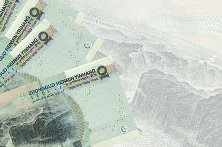 10 Chinese yuan bills lies in stack on background of big semi-transparent banknote. Abstract...