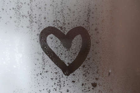 The heart is painted on the misted glass in the winterの写真素材
