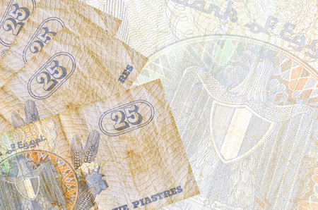 25 Egyptian piastres bills lies in stack on background of big semi-transparent banknote. Abstract...