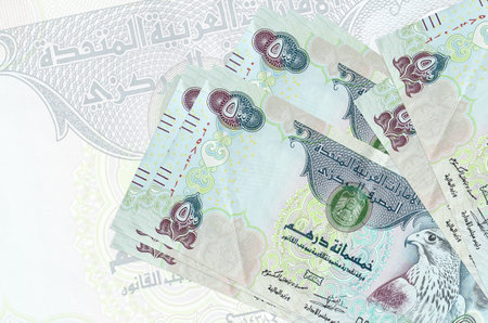 500 UAE dirhams bills lies in stack on background of big semi-transparent banknote. Abstract...