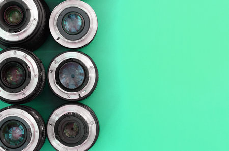 Several photographic lenses lie on a bright turquoise background. Space for textの写真素材