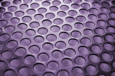 Black metal computer case panel mesh with holes on purple background. Abstract close up imageの写真素材