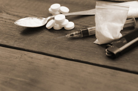 A lot of narcotic substances and devices for the preparation of drugs lie on an old wooden table. Drug dealer stuff. Heroin and methamphetamine in raw condition. Narcotic addiction conceptの写真素材