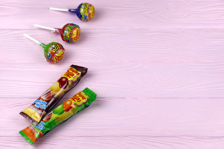 KHARKOV, UKRAINE - NOVEMBER 24, 2020: Chupa Chups products on pastel pink wooden table. Chupa Chups...