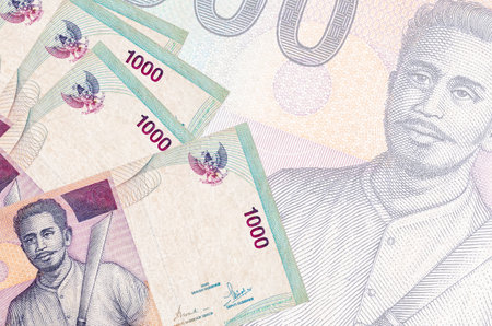 1000 Indonesian rupiah bills lies in stack on background of big semi-transparent banknote. Abstract...