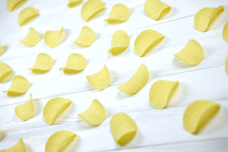 KHARKOV, UKRAINE - NOVEMBER 23, 2020: Many orange Pringles potato snack chips on white wooden table. Pringles is a brand of potato snack chips owned by Kellogg Companyのeditorial素材